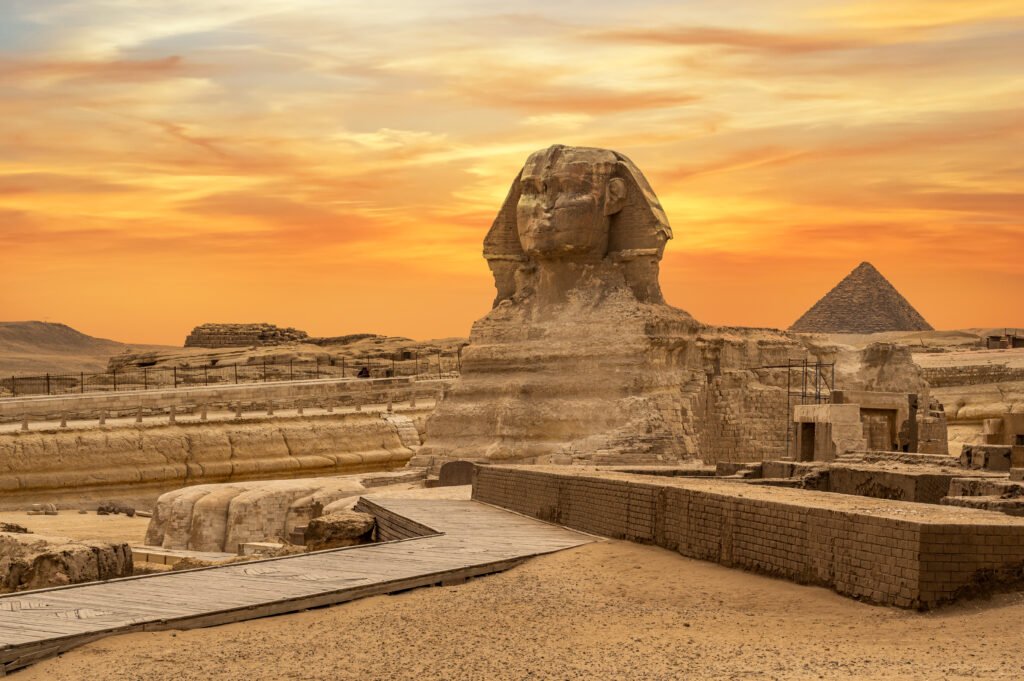 Landscape with Egyptian pyramids, Great Sphinx and silhouettes Ancient symbols and landmarks of Egypt for your travel concept to Africa in golden sunlight. The Sphinx in Giza pyramid complex at sunset